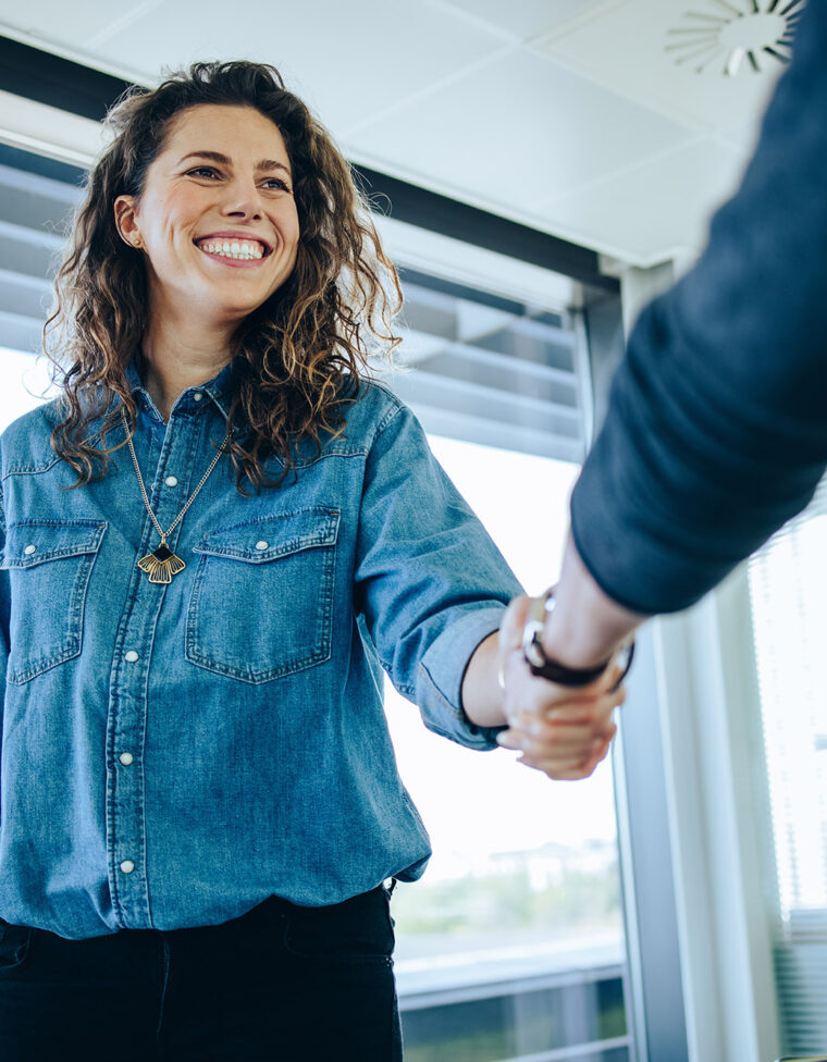 Recruitment manager shakes her hand with male candidate as he gets the job. Businesswoman handshake with a man in office meeting room.
