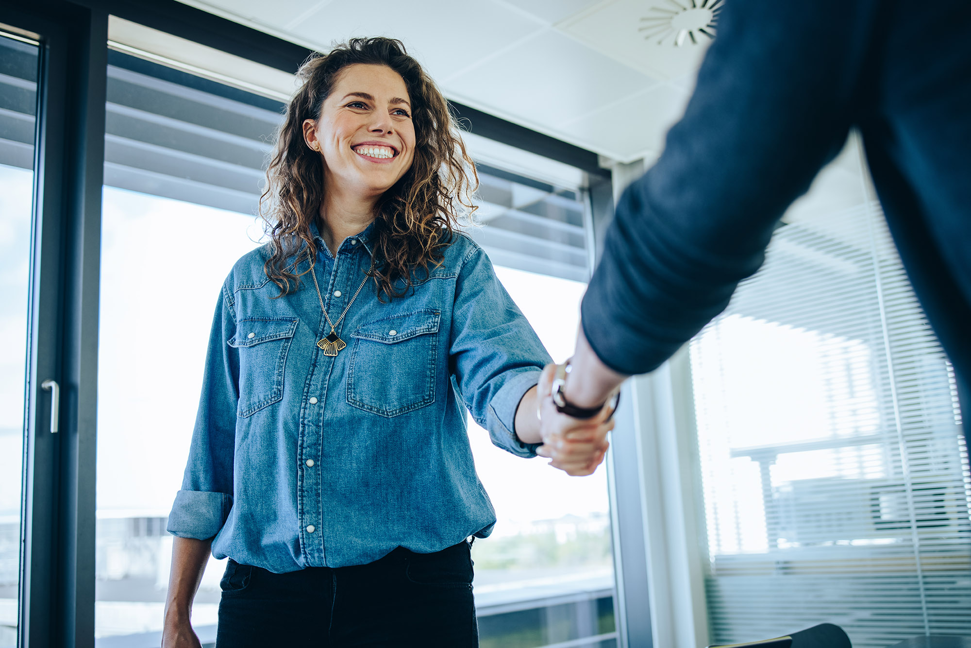 Recruitment manager shakes her hand with male candidate as he gets the job. Businesswoman handshake with a man in office meeting room.