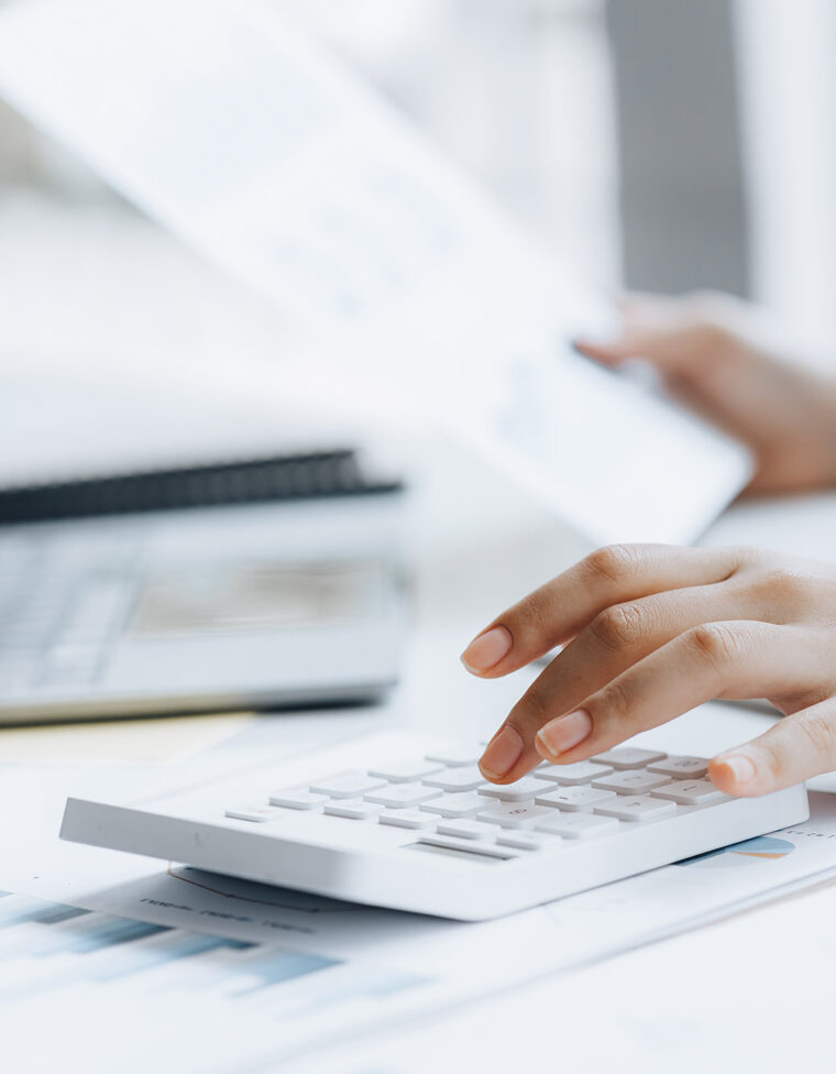 Businessman using a calculator to calculate numbers on a company's financial documents, he is analyzing historical financial data to plan how to grow the company. Financial concept.