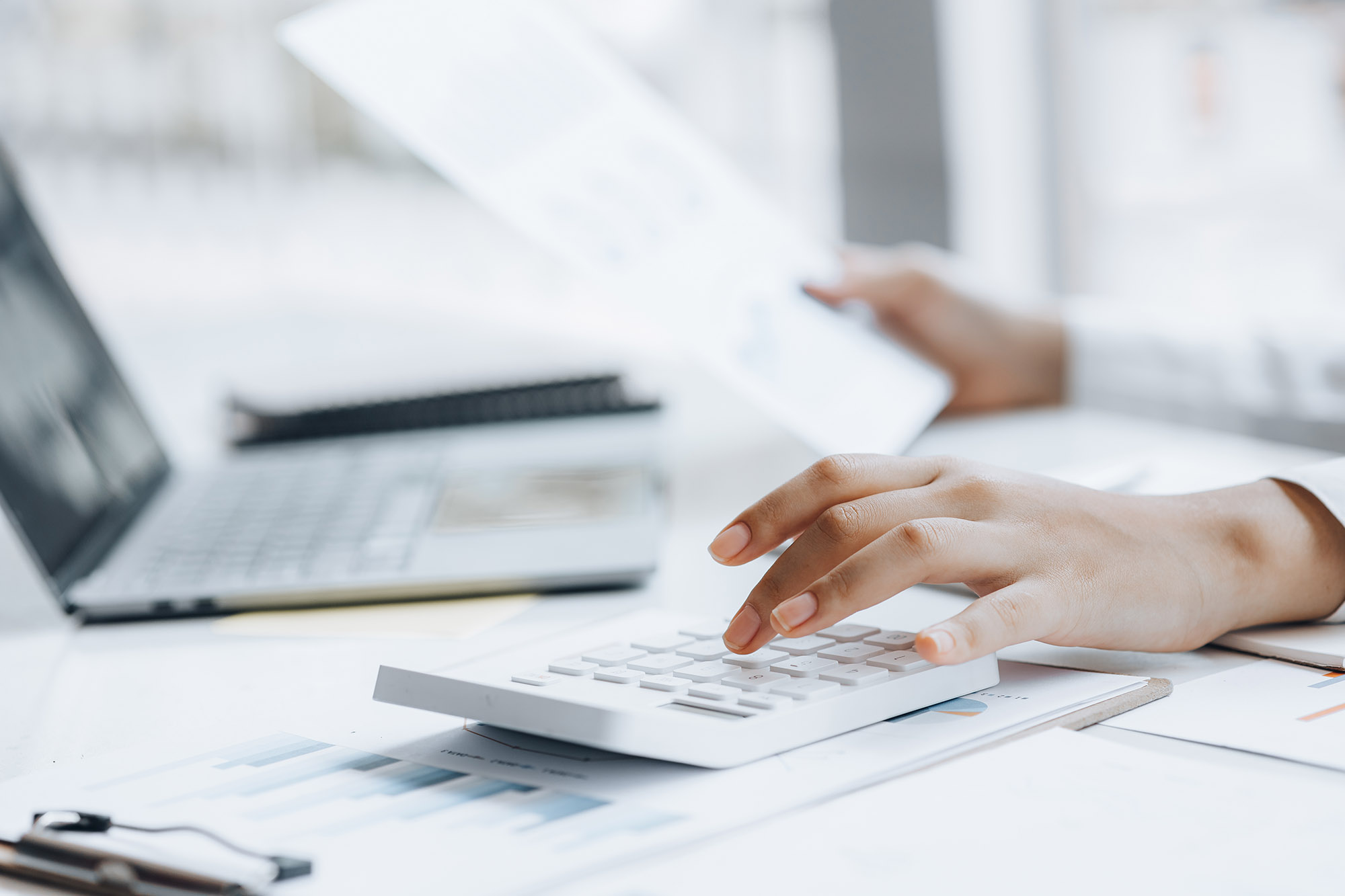 Businessman using a calculator to calculate numbers on a company's financial documents, he is analyzing historical financial data to plan how to grow the company. Financial concept.