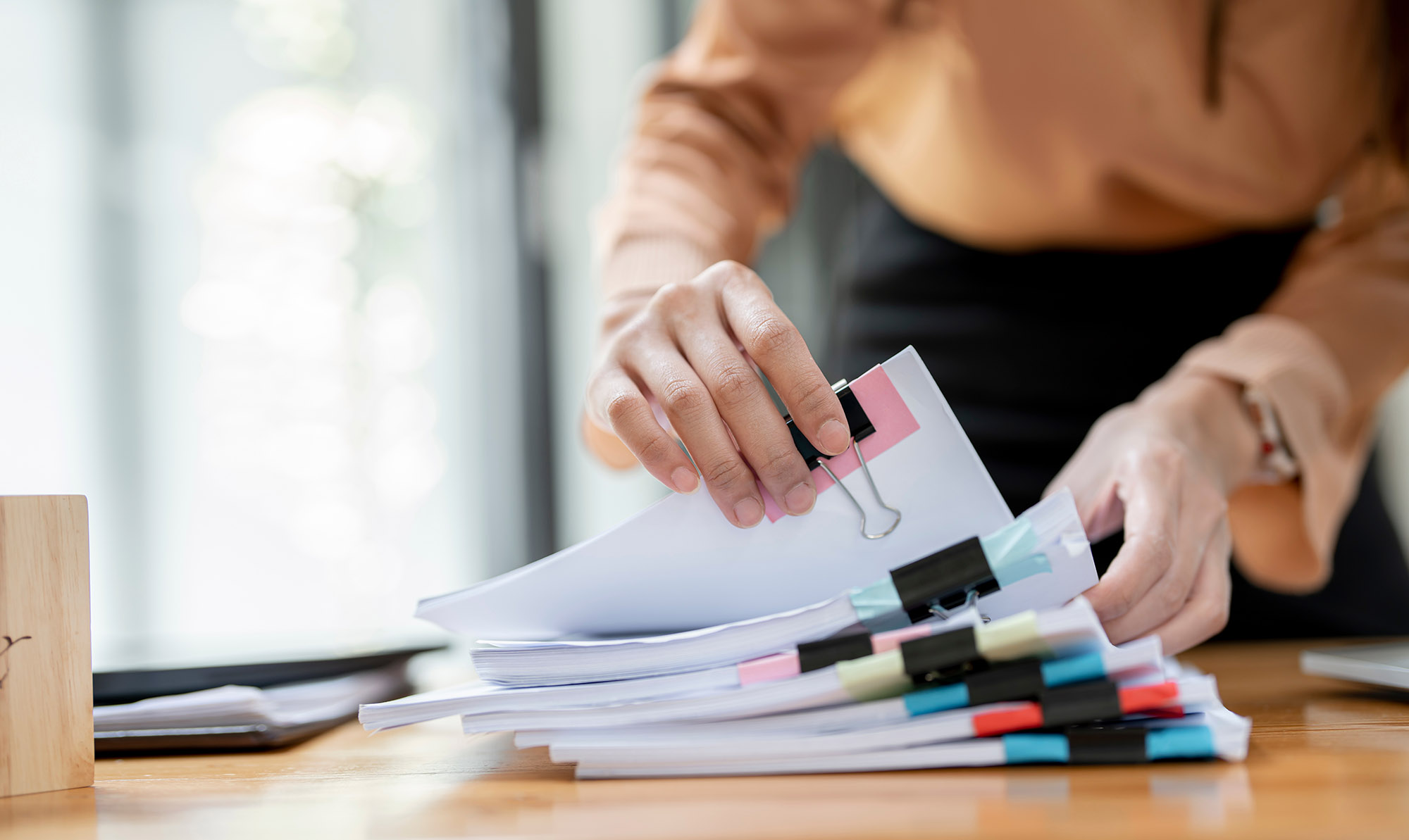 Businesswoman hands working in Stacks of paper files for searching and checking unfinished document achieves on folders papers at busy work desk office